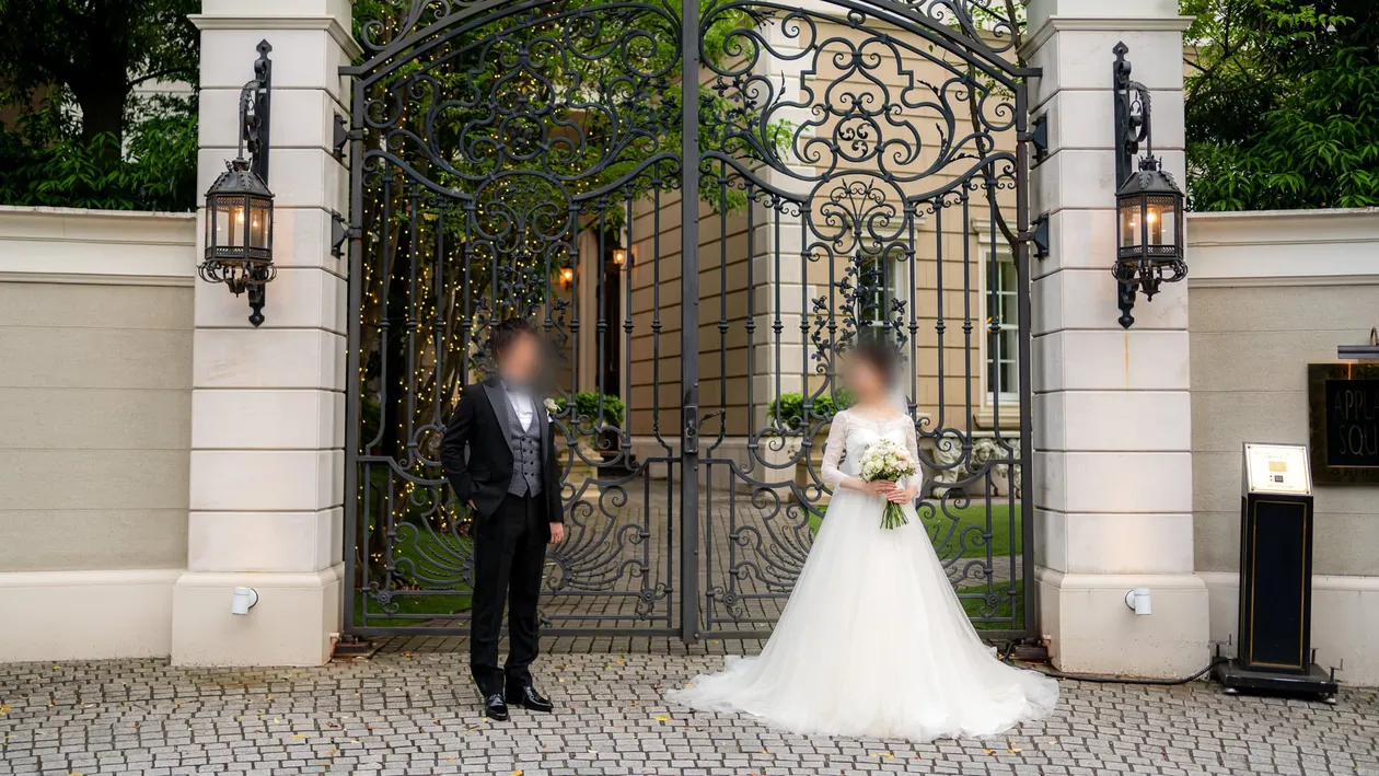 式場のゲート前に立つウェディングドレスの新婦とタキシードの新郎